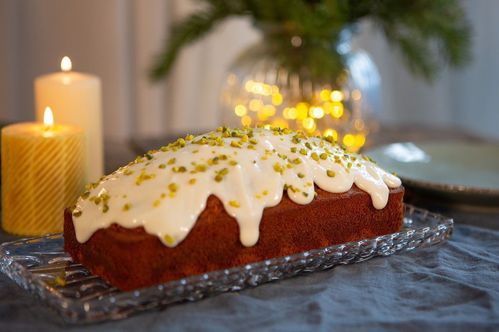 De chai honingcake met roomkaasglazuur staat op een gedekte tafel.