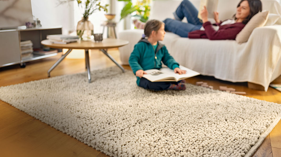 Vrouw bekleedt bankkussens in een gezellige woonkamer met woontextiel van natuurlijke materialen